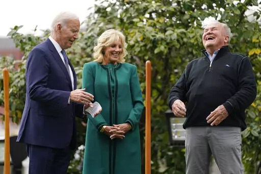 Dale Haney, the chief White House groundskeeper, right, laughs as he stands with President Joe Biden and first lady Jill Biden during a tree planting ceremony on the South Lawn of the White House, Monday, Oct. 24, 2022, in Washington. As of this month, Haney has tended the lawns and gardens of the White House for 50 years. (AP Photo/Evan Vucci)