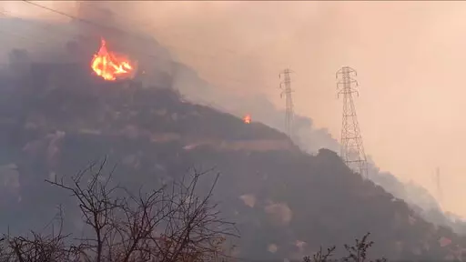 In this Saturday, Dec. 16, 2017, file image taken from video provided by the Santa Barbara County Fire Department, spot fires burn near power lines as heavy smoke fills the air from a wildfire in Santa Barbara, Calif. The nation's largest utility, Pacific Gas & Electric is poised to emerge from five years of criminal probation amid worries that it remains too dangerous to be trusted. Over the five years, the utility became an even more destructive force. More than 100 people have died and thousa