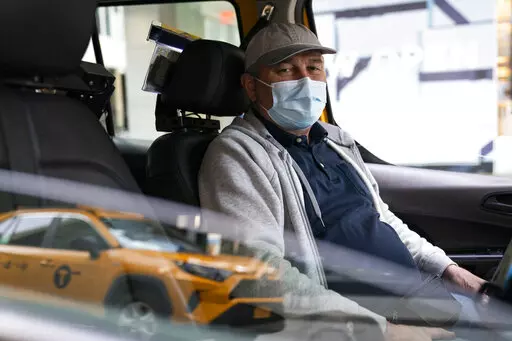 Nicolae Hent sits for a portrait in his taxi outside a midtown Manhattan hotel, in New York on March 19, 2021. “Not an easy year to go through in 2020," Hent said. "Hopefully, this one will be better, but God knows.” (AP Photo/John Minchillo)