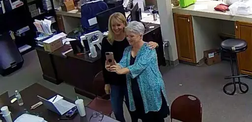 In this Jan. 7, 2021, image taken from Coffee County, Ga., security video, Cathy Latham (right) appears to take a selfie with a member of a computer forensics team inside the local elections office. Latham was the county Republican Party chair at the time. The computer forensics team was at the county elections office in Douglas, Ga., to make copies of voting equipment in an effort that documents show was arranged by Sidney Powell and others allied with then-President Donald Trump. (Coffee Count