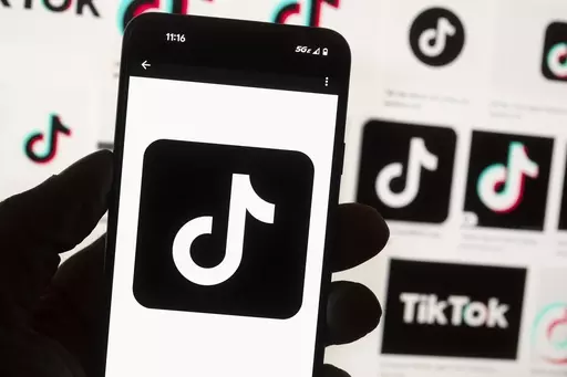 The TikTok logo is displayed on a mobile phone in front of a computer screen, Oct. 14, 2022, in Boston. TikTok is gearing up for a legal fight against a U.S. law that would force the social media platform to break ties with its China-based parent company or face a ban. A battle in the courts will almost certainly be backed by Chinese authorities as the bitter U.S.-China rivalry threatens the future of a wildly popular way for young Americans to connect online. (AP Photo/Michael Dwyer, File)