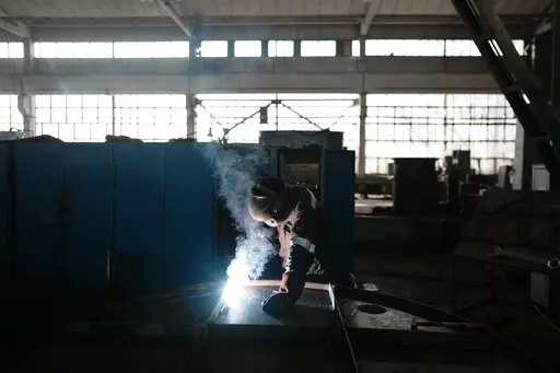 A worker welds part of a shelter in a plant of the Metinvest company, in Kryvyi Rih, Ukraine, Thursday, March 2, 2023. The plant, which is part of Renat Akhmetov's Metinvest metals and mining holding, ships metal shelters to the frontline. (AP Photo/Thibault Camus)
