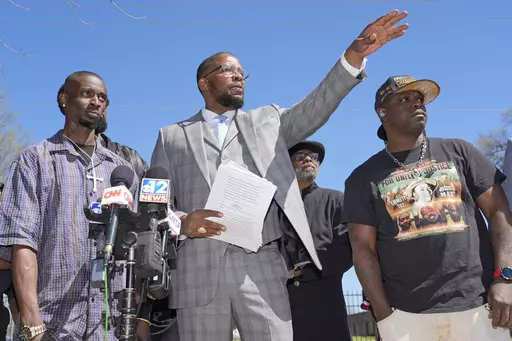 Michael Corey Jenkins, left, and Eddie Terrell Parker, right, stand with lead attorney Malik Shabazz, as they call on a federal judge Monday, March 18, 2024, at a news conference in Jackson, Miss., to impose the harshest possible penalties against six former Mississippi Rankin County law enforcement officers who committed numerous acts of racially motivated, violent torture on them in 2023. The six former law officers pleaded guilty to a number of charges for torturing them. (AP Photo/Rogelio V.