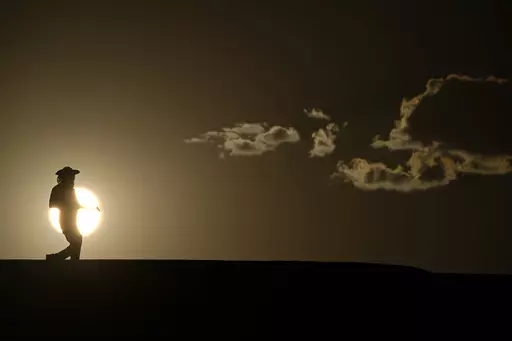 A person walks along a trail as the sun sets, Sunday, July 16, 2023, in Death Valley National Park, Calif. Human-caused global warming made July hotter for four out of five people on Earth, according to a new report issued Wednesday, Aug. 2, 2023, by Climate Central. (AP Photo/John Locher, File)
