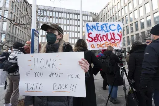 Protesters hold banners during a rally in front of the Office of Personnel Management, Monday, Feb. 3, 2025, in Washington. President Donald Trump is relying on a relatively obscure federal agency to reshape government. The Office of Personnel Management was created in 1979 by President Jimmy Carter and is the equivalent of the government's human resources department. It helps manage the civil service, including pay schedules, health insurance and pension programs. The agency has offered million