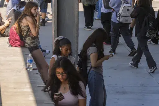 Students use their cellphones as they leave for the day the Ramon C. Cortines School of Visual and Performing Arts High School in downtown Los Angeles, Aug. 13, 2024. (AP Photo/Damian Dovarganes, File)