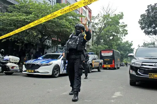 A police officer gestures at the crowd to move back as he guards a road leading to a police station where a bomb exploded in Bandung, West Java, Indonesia, Wednesday, Dec. 7, 2022. A man blew himself up Wednesday at a police station on Indonesia's main island of Java in what appeared to be the latest in a string of suicide attacks in the world's most populous Muslim nation. (AP Photo/Kholid Parmawinata)