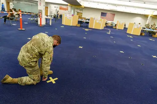 Rhode Island Army National Guard Staff Sgt. Andrew Bates pulls up tape marking a line at a coronavirus mass-vaccination site at the former Citizens Bank headquarters in Cranston, R.I., June 10, 2021. Up to 40,000 Army National Guard soldiers across the country - or about 13% of the force — have not yet gotten the mandated COVID-19 vaccine, and as the deadline for shots looms, at least 14,000 of them have flatly refused and could be forced out of the service. (AP Photo/David Goldman, File)
