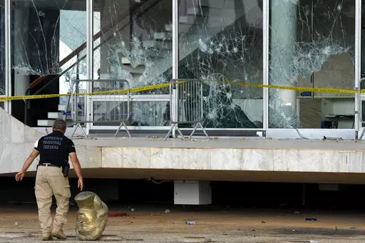 An agent walks past the head of a statue depicting the Greek goddess Themis, outside the Brazilian Supreme Court building that was damaged by supporters of Brazil's former President Jair Bolsonaro, in Brasilia, Brazil, Tuesday, Jan. 10, 2023. Bolsonaro supporters who refuse to accept his election defeat stormed Congress, the Supreme Court and presidential palace Sunday, a week after the inauguration of his leftist rival, President Luiz Inacio Lula da Silva. (AP Photo/Eraldo Peres)