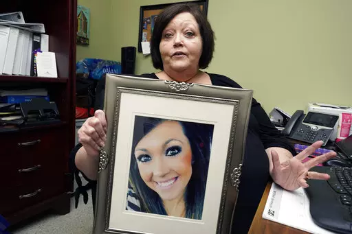 CORRECTS TO DELETE THE MIDDLE NAME AND SAY HARBOUR WAS A VICTIM - Denise Spears holds a portrait of her late step-daughter Marsha Harbour, in her Meridian, Miss., office, Tuesday, April 12, 2022. Although Marsha's husband, Truitt Pace, admitted killing his wife, he was free on bond while court proceedings were partially held up because the Mississippi Medical Examiner's Office autopsy report was delayed for a year, and the trial got held up further because of the pandemic and other factors. Harb