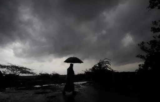 A villager holds an umbrella as dark clouds loom over Balasore district in Odisha, India, Tuesday, May 25, 2021, ahead of a powerful storm barreling toward the eastern coast. When it comes to measuring global warming, it’s not just the heat, it’s the humidity that matters in dangerous climate extremes, according to a study released on Monday, Jan. 31, 2022, in the Proceedings of the National Academy of Sciences in the U.S. (AP Photo/File)