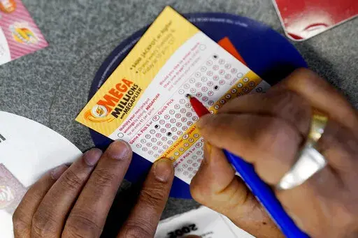 A customer fills out a Mega Millions lottery ticket at a convenience store in Northbrook, Ill., on Jan. 6, 2021. The holiday shopping season, for Mega Millions lottery ticket buyers, at least, is ramping up as officials say the estimated jackpot for the drawing the night of Tuesday, Dec. 27, 2022, has surpassed half a billion dollars. (AP Photo/Nam Y. Huh, File)