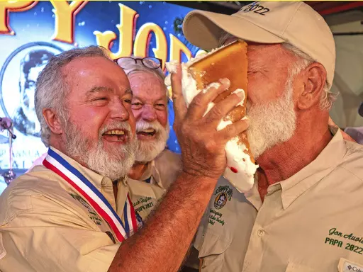 In this photo provided by the Florida Keys News Bureau, Zach Taylor, the 2021 "Papa" Hemingway Look-Alike Contest winner, shoves birthday cake into the face of 2022 winner Jon Auvil, Thursday, July 20, 2023, on the eve of Ernest Hemingway's 124th birthday anniversary, at Sloppy Joe's Bar in Key West, Fla. The birthday commemoration preceded the first round of the 2023 Hemingway Look-Alike Contest, a highlight of the island's annual Hemingway Days festival. The famed American author lived and wro