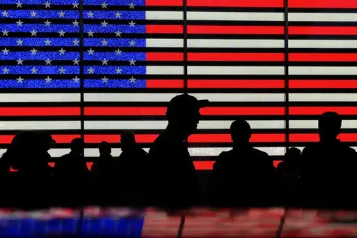 People gather near an electronic display of an American flag in Times Square in New York on Aug. 9, 2024. (AP Photo/Pamela Smith, File)