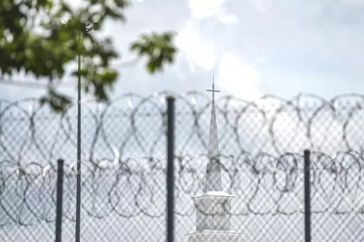 A church steeple peaks over the barbed-wire fence following the dedication of the newly constructed chapel at the Mississippi Correctional Institute for Women (MCIW) at Central Mississippi Correctional Facility in Pearl, Miss., June 15, 2023. A former Mississippi prison guard on Thursday, July 27, pleaded guilty to deprivation of an inmate's rights by using excessive force when she was a corrections officer at the Central Mississippi Correctional Facility, the U.S. Justice Department said. (Hann