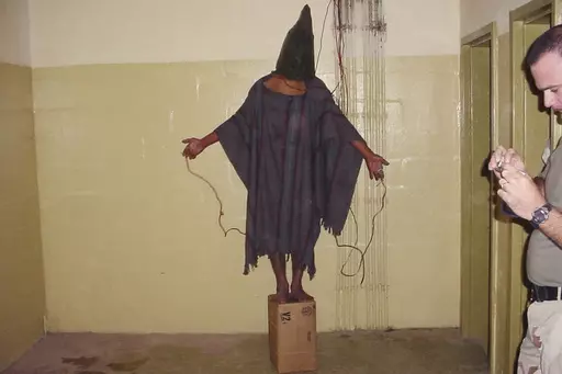 This late 2003 photo obtained by The Associated Press shows an unidentified detainee standing on a box with a bag on his head and wires attached to him in the Abu Ghraib prison in Baghdad, Iraq. A trial scheduled to begin Monday, April 15, 2024, in U.S. District Court in Alexandria, Va., will be the first time that survivors of Iraq’s Abu Ghraib prison will bring their claims of torture to a U.S. jury. Twenty years ago, photos of abused prisoners and smiling U.S. soldiers guarding them shocked