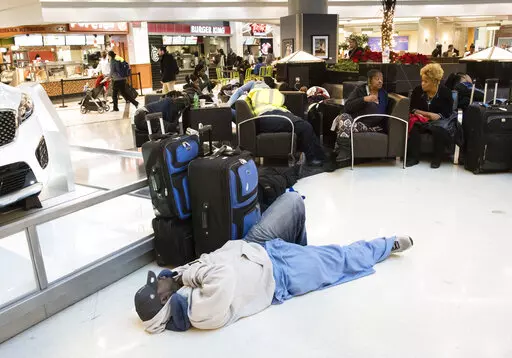 A man sleeps on the terminal floor at Hartfield-Jackson Atlanta International Airport on Dec. 18, 2017, in Atlanta. Transportation Secretary Pete Buttigieg has warned airlines that his department could draft new rules around passenger rights if the carriers don’t give more help to travelers trapped by flight cancellations and delays. The Transportation Department on Friday, Aug. 19, 2022, released a copy of the letters, which it said were sent to CEOs of the major U.S. airlines, their regional