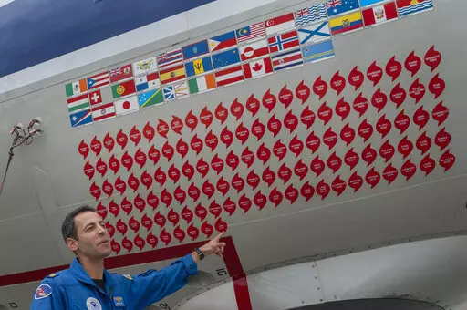 Lt. Commander Sam Urato, a P-3 pilot of National Oceanic and Atmospheric Administration, points to decals on the fuselage of the Lockheed WP-3D Orion 'hurricane hunter' aircraft representing the hurricanes it has penetrated during a hurricane awareness tour at Washington National Airport, Arlington, Va., Tuesday, May 3, 2022. Hurricane season starts Wednesday, June 1, 2022, and it's looking busy because every factor out there is pointing to another nasty year in the Atlantic. (AP Photo/Gemunu Am