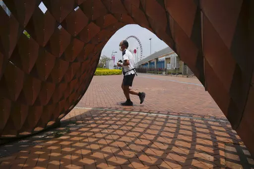 A man jogs in a park in Hong Kong, Thursday , May 5, 2022. Hong Kong on Thursday reopened beaches and pools in a relaxation of COVID-19 restrictions, while China's capital Beijing began easing quarantine rules for arrivals from overseas. (AP Photo/Kin Cheung)
