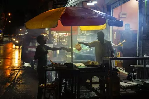 A street vendor sells food in Colombo, Sri Lanka, Wednesday, Dec. 28, 2022. In Sri Lanka, where the tourism-driven economy also has been hammered by political upheavals and shortages, the situation remains dire since COVID-19 hit in early 2020. (AP Photo/Eranga Jayawardena)