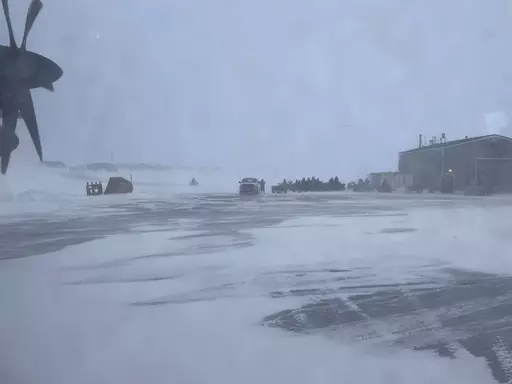 This March 28, 2023, photo shows townspeople in Gambell, Alaska, waiting in a snowstorm on four-wheelers to transport Alaska National Guard personnel from the air strip to the school for a ceremony. Sixteen Alaska National Guard members were honored for helping rescue the 11 crew members of a Navy plane that was shot down in 1955 by Soviet jet fighters and crash-landed about 8 miles from Gambell, on St. Lawrence Island, and 15 medals were presented posthumously. (AP Photo/Mark Thiessen)