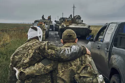 A Ukrainian soldier helps a wounded comrade on the road in reclaimed territory in the Kharkiv region, Ukraine, on Sept. 12, 2022. Some experts say the yearlong conflict that already has killed tens of thousands and reduced whole cities to smoldering ruins could drag on for many more years. (AP Photo/Kostiantyn Liberov, File)