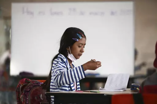 A student focuses on her lesson at Casa Kolping, an alternative education center where child migrants from two pastor-run shelters take classes every weekday morning, in Ciudad Juarez, Mexico, on Monday, March 28, 2022. Education is a big challenge for children on their migration journey, but opportunities like this give them a chance to catch up on academics and to find emotional support. (AP Photo/Christian Chavez)