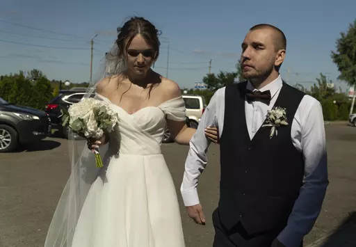 Bride Vladislava Ryabets, left, helps groom Ivan Soroka, right, to walk during their wedding day in Kyiv, Ukraine on Saturday, Sept. 9, 2023. Shrapnel blinded Soroka permanently on Aug. 2, 2022 when Russian mortar fire struck his retreating unit near Bakhmut during the war's longest and bloodiest battle. Despite Soroka's injury the couple has been determined to move forward. (AP Photo/Bela Szandelszky)