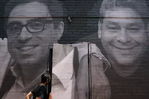 A woman steps through a door that is covered by a mural depicting American hostages and wrongful detainees who are being held abroad, July 20, 2022, in the Georgetown neighborhood of Washington. At left is Siamak Namazi, who has been in captivity in Iran since 2015. At right is Jose Angel Pereira, who has been imprisoned in Venezuela since 2017. The Biden administration has cleared the way for the release of five American citizens detained in Iran, including Namazi, by issuing a blanket waiver f