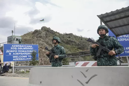 Azerbaijani servicemen guard the Lachin checkpoint on the in Azerbaijan, Sunday, Oct. 1, 2023. Astsetrayn was one of the last residents of Nagorno-Karabakh to drive out of the region in his own vehicle as part of a grueling weeklong exodus of over 100,000 people — more than 80% of the residents — after Azerbaijan reclaimed the area in a lightning military operation. (AP Photo/Aziz Karimov)