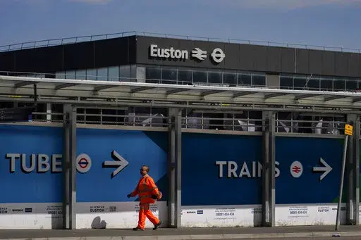 A construction worker walks past Euston station, in London, Tuesday, June 21, 2022. Tens of thousands of railway workers walked off the job in Britain on Tuesday, bringing the train network to a crawl in the country’s biggest transit strike for three decades. (AP Photo/Alberto Pezzali)