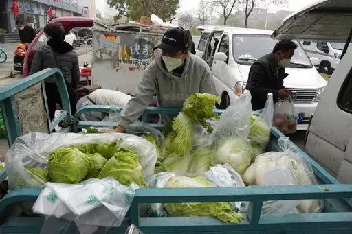 Residents buy fresh vegetables from street vendors as restaurants are closed in some districts in Beijing, Thursday, Nov. 24, 2022. China is expanding lockdowns, including in a central city where factory workers clashed this week with police, as its number of COVID-19 cases hit a daily record. (AP Photo/Ng Han Guan)