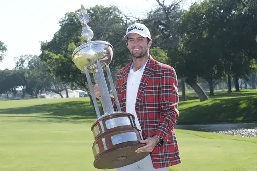 Davis Riley poses with the winner's trophy at the Charles Schwab Challenge golf tournament at Colonial Country Club in Fort Worth, Texas, Sunday, May 26, 2024. (AP Photo/LM Otero