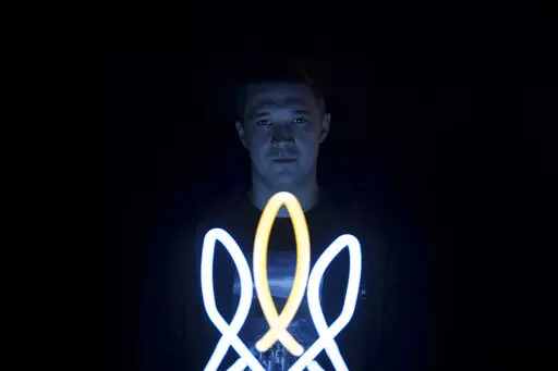 Mykhailo Fedorov, Ukrainian minister of digital transformation, poses for a photo illuminated by a lamp in the shape of a Ukrainian trident, a national symbol, in his office in Kyiv, Ukraine, Wednesday, Dec. 21, 2022. The Ukrainian government minister in charge of technology says his country has bought some 1,400 drones, mostly for reconnaissance, and is now developing air-to-air combat ones that can attack the drones Russia is using against Ukrainians. In a recent interview with The Associated 