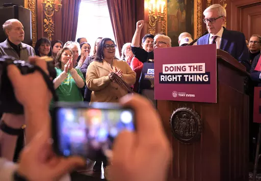 Supporters of Wisconsin Gov. Tony Evers' plan to re-draw the state's legislative maps react as he stands at a podium during the bill-signing event at the Wisconsin State Capitol in Madison, Wis. Monday, Feb. 19, 2024. Democrats tried unsuccessfully for more than a decade to overturn the Republican-drawn maps. But it wasn’t until control of the state Supreme Court flipped in August after the election of liberal Justice Janet Protasiewicz that Democrats found a winning formula. (John Hart/Wiscon