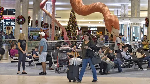 Holiday travelers pass by "Phoebe" the Flamingo at the Tampa International Airport, Friday, Dec. 22, 2023, in Tampa, Fla. Conditions were mostly nice for travelers flying ahead of and on Christmas Day this year, but some naughty disruptions plagued those flying with Southwest Airlines again this year. By midday Monday, Dec. 25, only 138 flights within, into or out of the U.S. had been canceled and 1,366 were delayed, according to FlightAware, a tracking website. (AP Photo/Chris O'Meara, File)