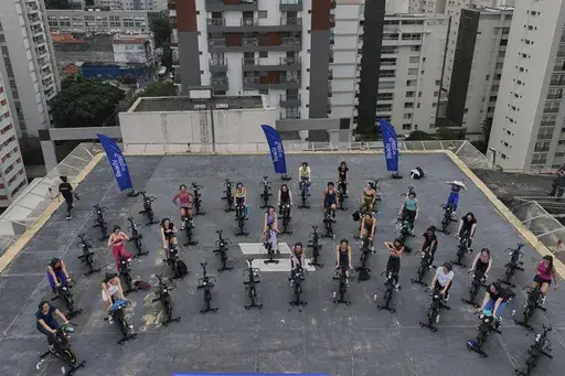 Women attend a spinning class on a hotel building's helipad in Sao Paulo, Tuesday, March 18, 2025. (AP Photo/Andre Penner)