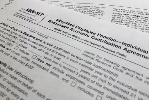 In this April 2, 2018, file photo, an IRS Form 5305, Simplified Employee Pension — Individual Retirement Accounts Contribution Agreement is shown in New York. Companies have long helped their workers save for retirement through 401(k)s and other workplace plans. But recent SECURE 2.0 legislation has blessed a newer trend: employers creating emergency savings options that could encourage workers to save more and avoid raiding their retirement funds. (AP Photo/Jenny Kane, File)