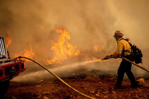 A firefighter sprays water while trying to keep the Electra Fire from spreading in the Pine Acres community of Amador County, Calif., on Tuesday, July 5, 2022. (AP Photo/Noah Berger)