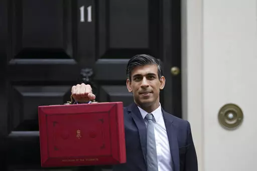 Britain's Chancellor of the Exchequer Rishi Sunak holds up the traditional ministerial red dispatch box as he leaves for the House of Commons to deliver the Budget in London, Oct. 27, 2021. Revelations that Prime Minister Boris Johnson and his staff partied while Britain was in a coronavirus lockdown have provoked public outrage and led some members of his Conservative Party to consider ousting their leader. If they manage to push Johnson out — or if he resigns — the party would hold a leade