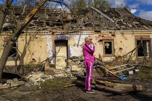 Iryna Martsyniuk, 50, stands next to her house, heavily damaged after a Russian bombing in Velyka Kostromka village, Ukraine, Thursday, May 19, 2022. Martsyniuk and her three young children were at home when the attack occurred in the village, a few kilometres from the front lines, but they all survived unharmed. (AP Photo/Francisco Seco)