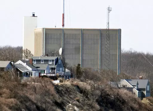 A portion of the Pilgrim Nuclear Power Station is visible beyond houses along the coast of Cape Cod Bay, in Plymouth, Mass., March 30, 2011. Pilgrim, which closed in 2019, was a boiling water reactor. Water constantly circulated through the reactor vessel and nuclear fuel, converting it to steam to spin the turbine. The water was cooled and recirculated, picking up radioactive contamination. (AP Photo/Steven Senne, File)