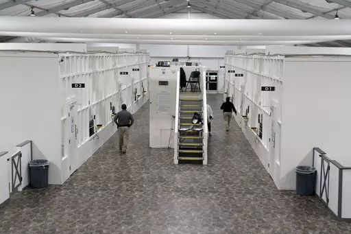 Agents walk among rooms at a Border Patrol holding facility on Dec. 15, 2023, in Tucson, Ariz. U.S. asylum officers were instructed nearly a year ago to apply a higher screening standard on people who cross the border illegally to claim asylum after passing through another country. But they are too understaffed to have much impact. (AP Photo/Gregory Bull, File)