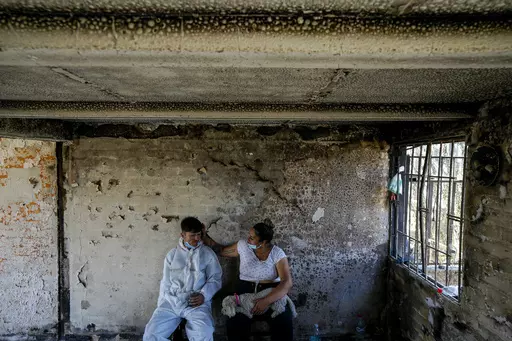 Camila Lange, who is 7-months-pregnant, and her husband Felipe Corvalan sit with their dog Florencia inside their home that was burned by a deadly wildfire in Vina del Mar, Chile, Monday, Feb. 5, 2024. (AP Photo/Esteban Felix)