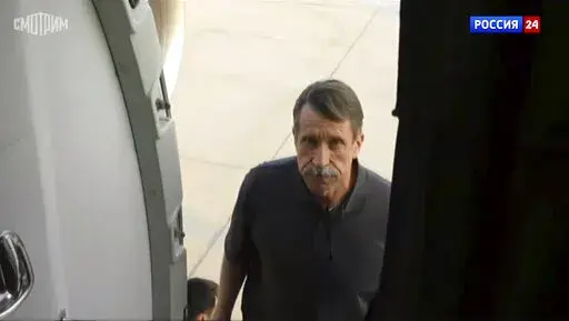 In this image taken from video provided by the RU-24 Russian Television on Friday, Dec. 9, 2022, Russian citizen Viktor Bout, right, who was exchanged for U.S. basketball player Brittney Griner, boards a Russian plane after a swap, in the airport of Abu Dhabi, United Arab Emirates. Russian arms dealer Bout, who was released from U.S. prison in exchange for WNBA star Griner, is widely labeled abroad as the "Merchant of Death" who fueled some of the world's worst conflicts but seen at home as a sw