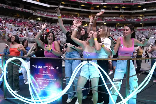 Concertgoers dance during Coldplay's Music of the Spheres world tour on Thursday, May 12, 2022, at State Farm Stadium in Glendale, Ariz. The band has included energy-storing stationary bikes to their latest world tour, encouraging fans to help power the show as part of a push to make the tour more environmentally friendly. (Photo by Rick Scuteri/Invision/AP)