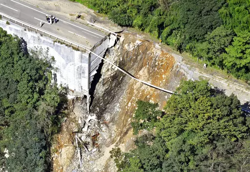 A collapsed road is seen following a typhoon in Morotsuka, Miyazaki prefecture, Tuesday, Sept. 20, 2022. A tropical storm that dumped heavy rain as it cut across Japan moved into the Pacific Ocean on Tuesday after killing a few and injuring more than 100, paralyzing traffic and leaving thousands of homes without power.(Kyodo News via AP)