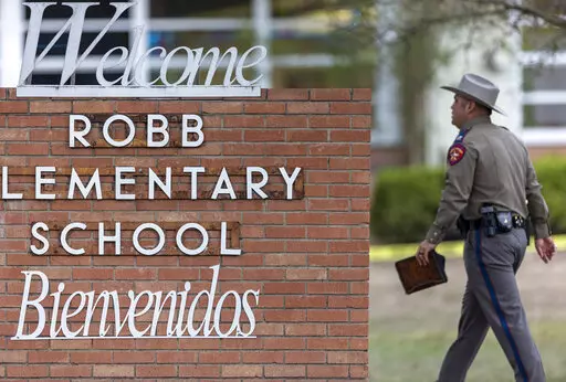 A state trooper walks past the Robb Elementary School sign in Uvalde, Texas, Tuesday, May 24, 2022, following a deadly shooting at the school. (William Luther/The San Antonio Express-News via AP, File)