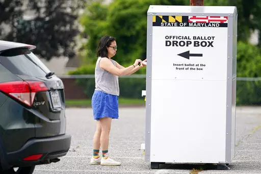 A woman drops a ballot into a drop box while casting her vote during Maryland's primary election, Tuesday, July 19, 2022, in Baltimore.  Whether a state requires voters to request an absentee ballot or participates in universal mail-in voting, all ballots cast by mail or dropped off at a drop box are vetted to ensure their legitimacy.(AP Photo/Julio Cortez, File)