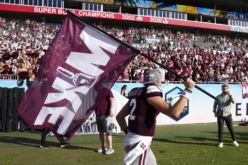Mississippi State quarterback Will Rogers runs with a "Mike" flag in honor of former coach Mike Leach at the end of the ReliaQuest Bowl NCAA college football game Monday, Jan. 2, 2023, in Tampa, Fla. Mississippi State defeated Illinois. Leach died on Dec. 13, 2022, from a heart condition. (AP Photo/Chris O'Meara)